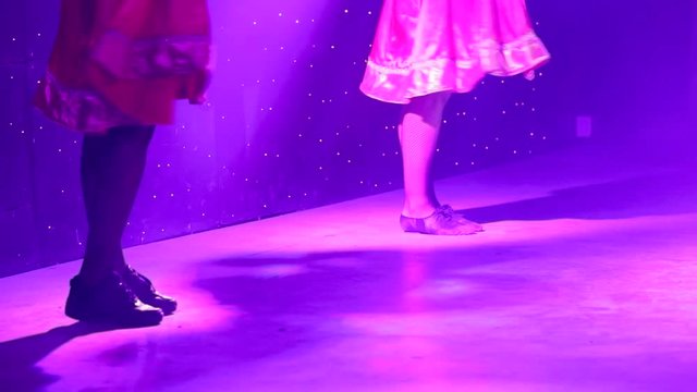 feet of dancers on stage during performance. Colored light and stage smoke on stage.