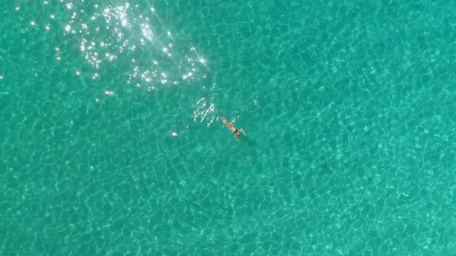 Aerial view of a woman floating in the sea of Ithaca island.