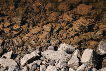 lakeside beach details with sand, rocks and blur background