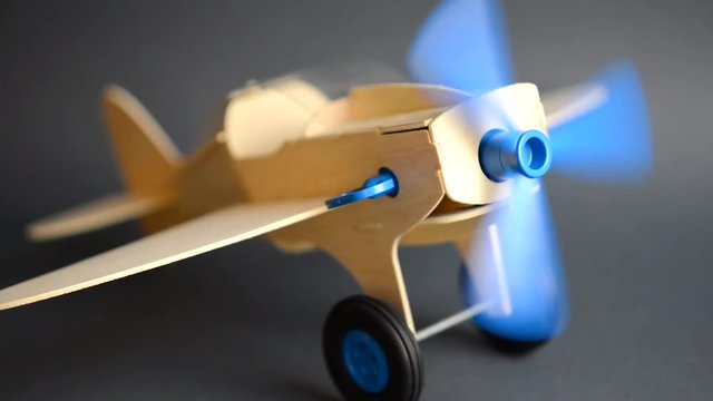 VIDEO, Wooden airplane model with rotating propeller standing on grey background