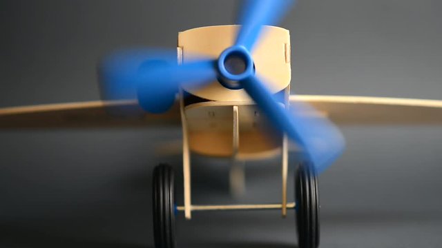 VIDEO, Wooden airplane model with rotating propeller standing on grey background