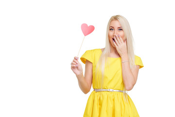 Valentine's Day.  Young blond woman with pink heart on white isolated background. portrait of smiling woman in yellow dress