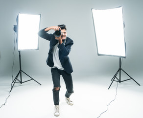 Young indian man photographer taking photo with professional digital camera, focus on hand and lens...