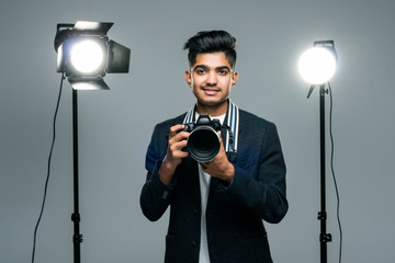 Young indian male photographer in studio with professional lighting equipment