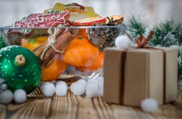 New year's gift stands on a wood table next to the oranges, tangerines, snowflakes and Christmas Toys