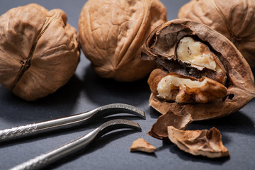 Brown premium raw organic walnuts and nutcracker in wooden bowl on natural stone background