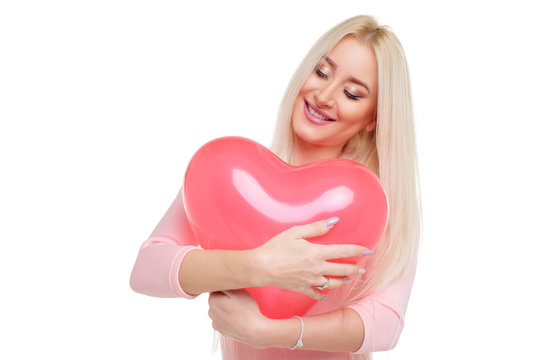 Beautiful young blond woman with heart shape pink air balloon on white isolated background. Woman on Valentine's Day. Symbol of love - Image