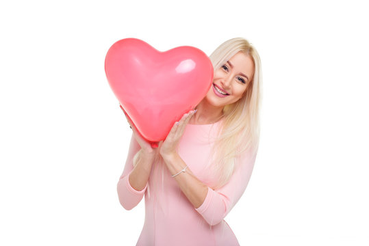 Beautiful young blond woman with heart shape pink air balloon on white isolated background. Woman on Valentine's Day. Symbol of love - Image