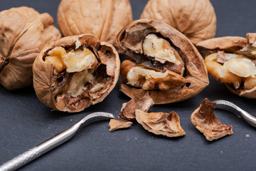 Brown premium raw organic walnuts and nutcracker in wooden bowl on natural stone background