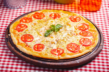 Pizza Margherita (Margarita) with tomatoes and cheese on wooden board. Close up