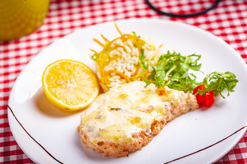 Salmon fillet served with risotto, arugula salad and lemon on white plate. Close up