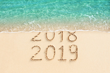 New Year concept - 2018 and 2019 written on sand beach