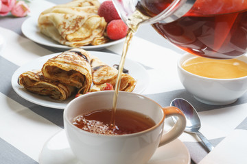 Fresh, tasty breakfast with tea and buns on a light background.