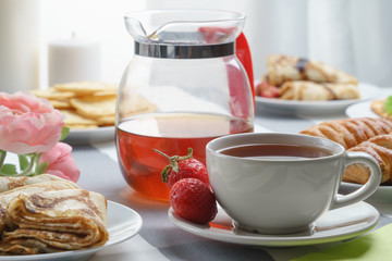 Fresh, tasty breakfast with tea and buns on a light background.