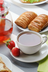 Fresh, tasty breakfast with tea and buns on a light background.