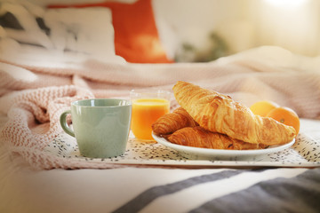 Breakfast tray on bed with fresh croissants coffee and orange juice