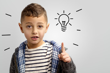The boy holds his index finger upwards and points to a painted light bulb. Idea.