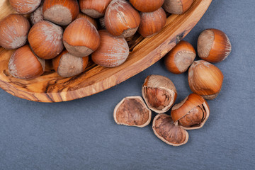Fresh organic high quality hazelnuts, filberts in wooden bowl on natural stone background.