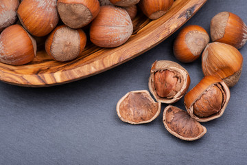 Fresh organic high quality hazelnuts, filberts in wooden bowl on natural stone background.