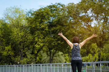 Fototapeta na wymiar Asian woman wearing a sports wear, standing arms back in a garden with many trees. A good source of oxygen. Make the exercise feel fresh. And the respiratory system works well in the summer.