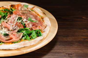 Pizza with ham and vegetables on wooden table