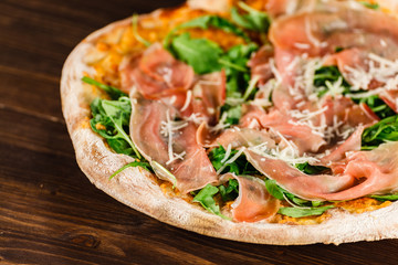 Pizza with ham and vegetables on wooden table