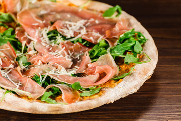 Pizza with ham and vegetables on wooden table