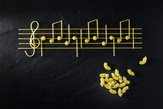 Musical Italian pasta in the form of notes, isolated on a black textural background.