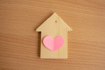 Obraz na płótnie Canvas model wood house with pink paper heart on wood table.home care concept.