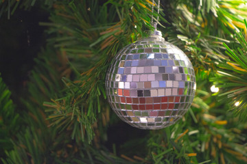 Mirrored shiny silver disco ball decorate on Christmas tree.