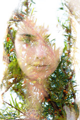 Double exposure portrait of a naturally beautiful woman softly touching her face combined with clusters of small red circular fruits hanging from branches