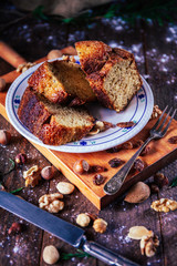 Pieces of homemade sponge cake of nuts, hazelnuts, walnuts and raisins in rustic background