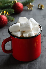 Red cup with hot cocoa or chocolate and marshmallows on black background.