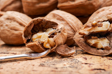 Brown premium raw organic walnuts and nutcracker on natural cork background.
