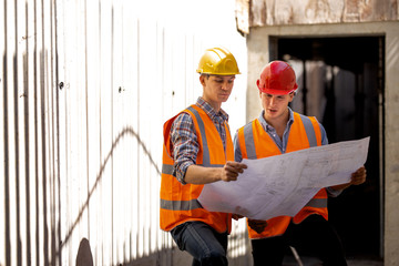 Structural engineer and construction manager dressed in work clothes and hard bats explore...