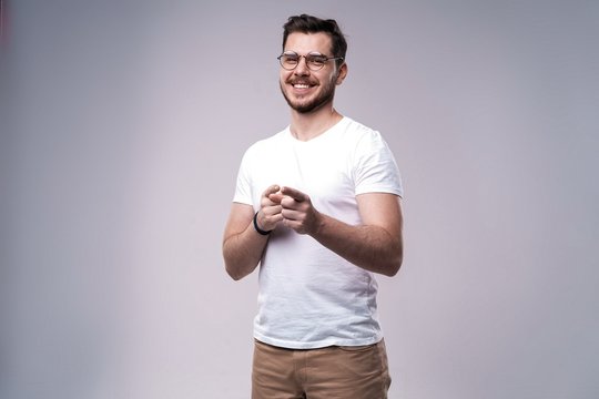 smiling young casual man presenting something on gray background.