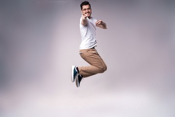 handsome man casual dressed celebrating and jumping on gray background