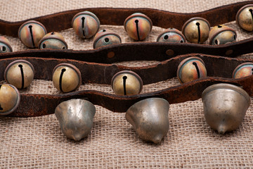Antique vintage oxidize brass sleigh bells on leather strap and burlap background