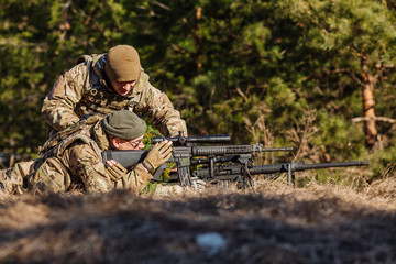 Instructor with operator aiming machine gun at firing range. People and military concept