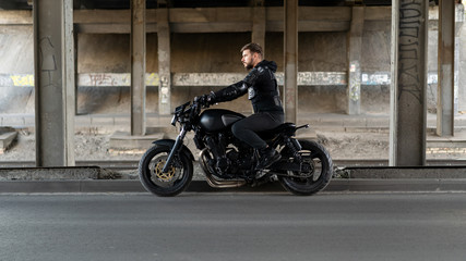 Obraz na płótnie Canvas Guy on a black motorcycle motorcycle stay on the road under the bridge