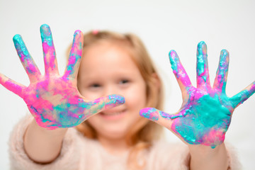 Happy child playing with paint, the girl has paint on hands and fingers