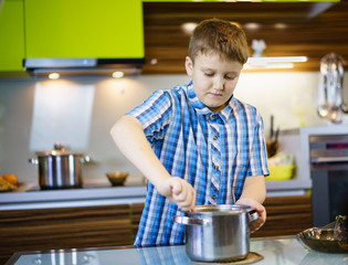 The boy enthusiastically cooks in the kitchen for himself to eat