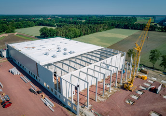 Industriehallenbau - neue Industriehalle mit großem Baukran davor, Luftaufnahme
