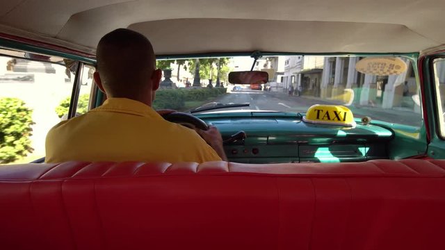 Cuban taxi driver driving 1950's american vintage classic car in old streets of Vieja neighborhood Havana, Cuba