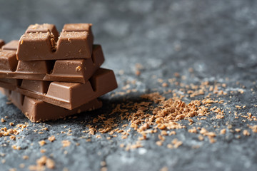 Selective focus Broken chocolate pieces and cocoa powder on  stone background