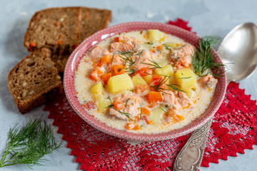 Creamy soup with salmon, vegetables and fresh dill in a bowl.