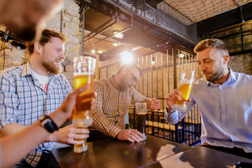 Sad tired casual man sitting with his friends in a bar and drinking beer. Looking lonely and in problems.