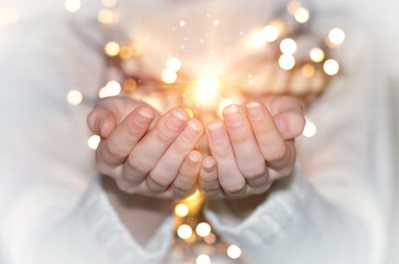 Magic particles emanating from female hands. Christmas background with bokeh