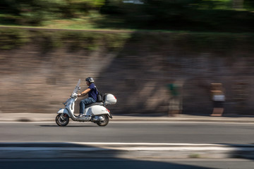 Italian man are riding scooter in the streets of Rome. Motorbike, roman, long exposure shot.