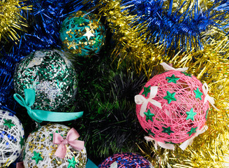 Fototapeta na wymiar Christmas balls on multi-colored tinsel. Handmade Christmas balls close-up.
